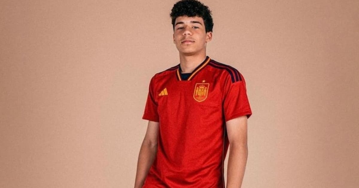 Vestido com o uniforme da seleção da Espanha, Enzo Alves pisa na bola