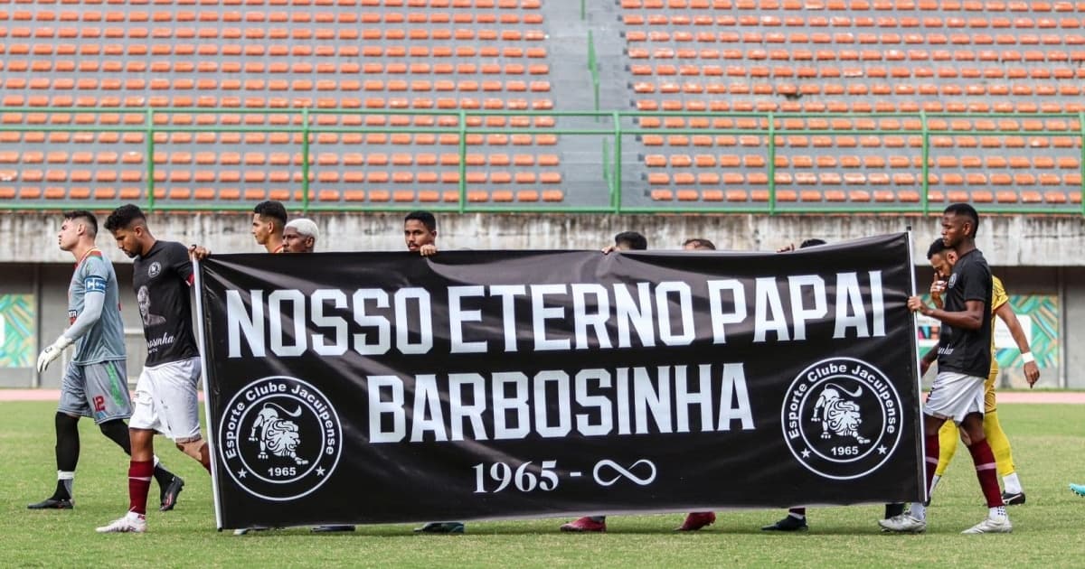 Jogadores do Jacuipense segurando cartaz contendo homenagem a Barbosinha